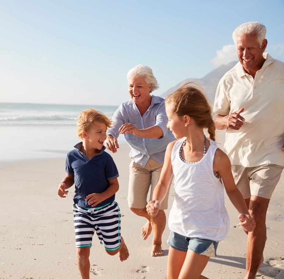 Grandparents running with their grandchildren on the beach